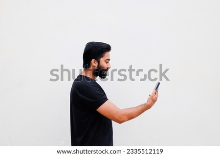 Young Pakistani or Indian man using mobile phone isolated against white background