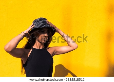 dark-haired girl with hat. as background an orange wall