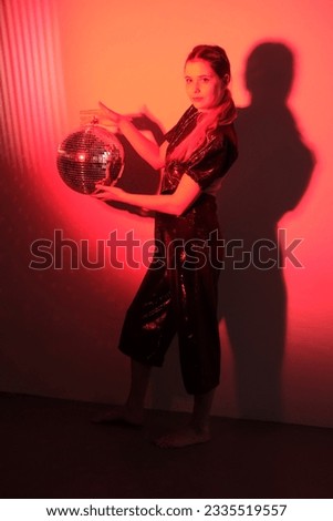 Women in the red flashlight in studio with disco ball in her hands