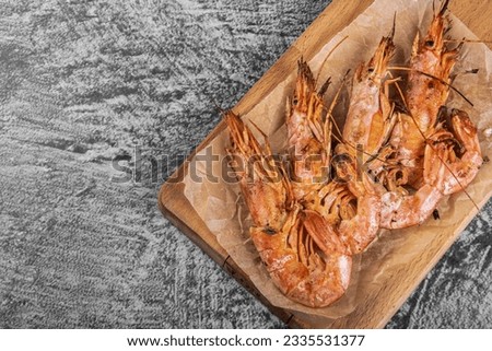 Grilled large langoustines on on wooden board. Grilled shrimps. BBQ roasted Giant shrimps Langoustine. Seafood for a healthy diet. Top view.