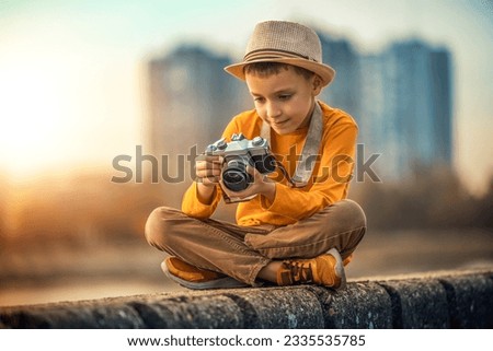 Autumn portrait of cute little caucasian boy outdoor.Little boy taking picture ,using vintage film camera.