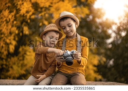 Autumn portrait of cute little caucasian boys outdoor.Little boy taking picture ,using vintage film camera.