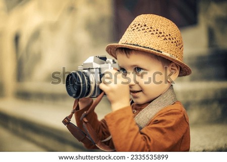 Autumn portrait of cute little caucasian boy outdoor.Little boy taking picture ,using vintage film camera.