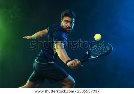 Padel Tennis Player with Racket in Hand. Paddle tenis, on a blue background. Download in high resolution. Royalty-Free Stock Photo #2335537937