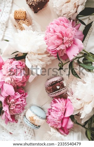 Macaroons and peonies, flat lay top view.