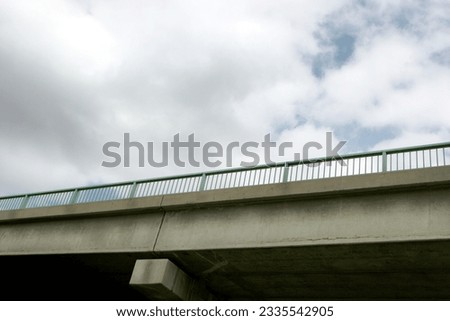 Horizontal photo looking up at an overpass with a dark cloudy sky behind.