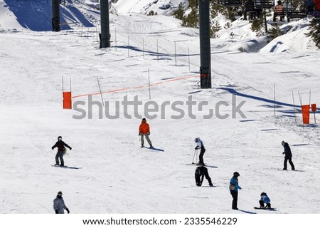 View of a group o people practicing snow boarding and skiing at a ski resort. 