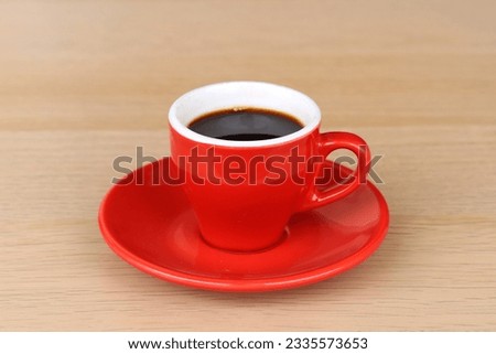 Black coffee drink served on red cup in wooden table
