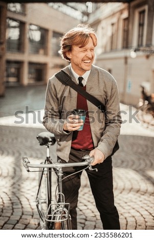 Mature man pushing his bicycle in the city and having coffee