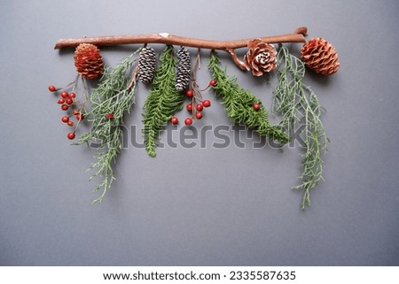 Winter green, berries and acorn decoration on gray background. Winter holiday composition. Christmas decoration.