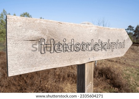 Wooden sign in the heathland with the inscription heath adventure trail in german language