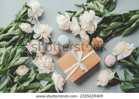 Gift box with bow, white peonies and sweet macaroons, holiday concept.
