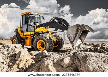 Powerful bulldozer or loader moves the earth at the construction site against the sky. An earthmoving machine is leveling the site. Construction heavy equipment for earthworks Royalty-Free Stock Photo #2335646389