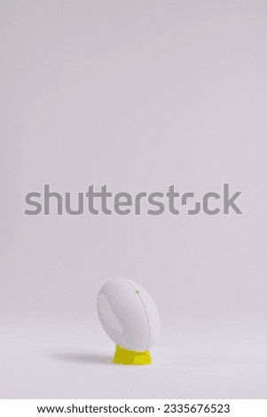 White rugby ball on yellow stand with copy space on white background. Rugby, sport, international, competition and games digitally generated image.