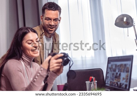 Young couple of photographers working with laptop at the working place with computers in the studio