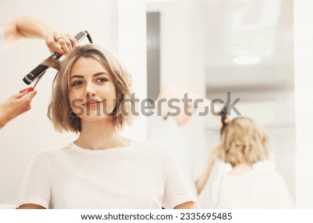 Barber salon. Customer service in barbershop room, create making hairdress. Hairdresser lady curling hairstyle for lovely young woman in hair salon. Concept of hairstyle, lifestyle. Copy ad text space