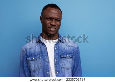 portrait of a young handsome with dark skin american guy dressed stylishly in casual clothes on a blue background with copy space