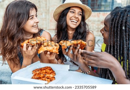 Three young female friends eating pizza sitting outside - Happy women enjoying street food in the city - Italian food culture and european holidays concept Royalty-Free Stock Photo #2335705589