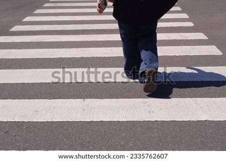 A woman confidently walks across the road on a zebra crossing, exemplifying pedestrian safety and elegance amid the bustling cityscape.