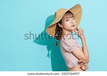 Portrait of young Asian woman in swimsuit on blue background