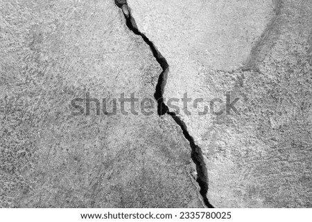 Big crack on old plastering wall. Long winding crack in cement surface of an old building. Black and white photo. Copy space. Selective focus. Royalty-Free Stock Photo #2335780025