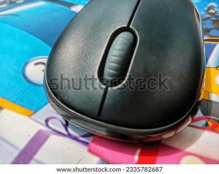 A Mouse lying on a colored carpet that has a cartoon image on it