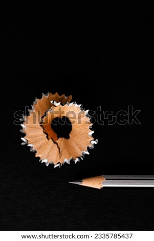 Top close up shot of a pencil shaving in round design shot over black background -Classroom concept.
