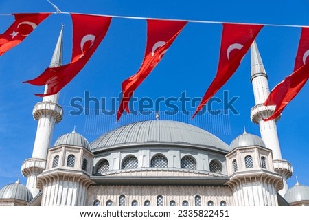A picture of the Taksim Mosque with many Turkish flags hanging nearby.