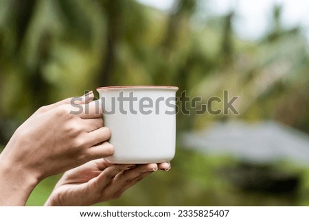 Skillfully arranged mockup showcases a woman wearing a white blank mug, striking a simple pose while presenting it, perfect for enhancing your visuals