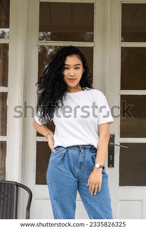 A beautifully staged mockup image exhibits a woman in a blank white shirt, striking a pose that complements your designs
