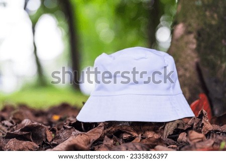 The mockup features a white blank bucket hat in the serene backdrop of nature, tastefully arranged with a simple and appealing style