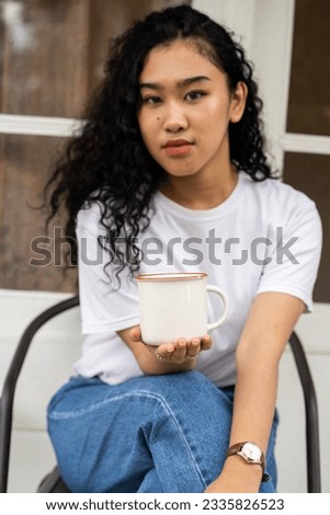 An artfully crafted mockup displays a woman showcasing a white mug with a simple pose, adding sophistication to your design presentations