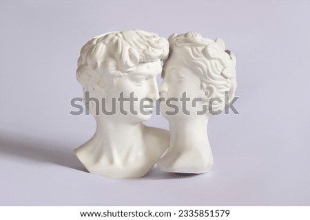 Two antique statue's heads isolated on a white background. Relationships of man and woman. Love, romance, kiss, tenderness. Modern design. Contemporary art. David and Aphrodite