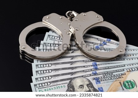Handcuffs with cash money isolated on black background. Cash bail reform, bail bond and cashless bail concept. Royalty-Free Stock Photo #2335874821