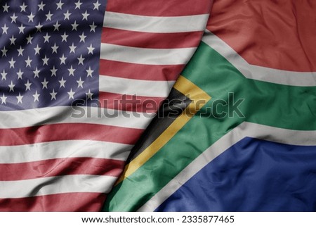 big waving colorful flag of united states of america and national flag of south africa . macro