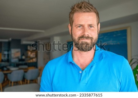 Close up headshot portrait of smiling 30s Caucasian man look at camera posing in own flat or apartment.