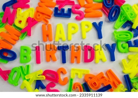 This stock image features the words "Happy Birthday" made from colorful letter magnets on a plain background. background
