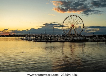 Illuminated ferris wheel at National Harbor near the nation capital of Washington DC at sunset with marina in the foreground Royalty-Free Stock Photo #2335914201