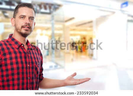 Man with red shirt over shopping center background. Showign something