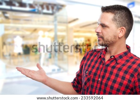 Man with red shirt over shopping center background. Showing something