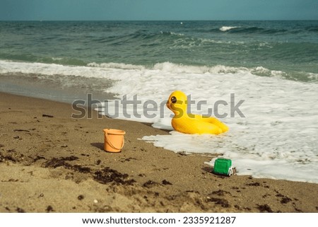 lifebuoy yellow duck on the sand on the beach on a summer day Royalty-Free Stock Photo #2335921287