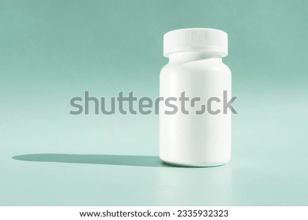 White Bottle Of Medication Pills Or Vitamins On Green Or Turquoise, Mint Background With Shadow. Horizontal Plane. Copy Space For Text. Healthy Bio Supplements. Pharmacology. Design Or Mockup. Royalty-Free Stock Photo #2335932323