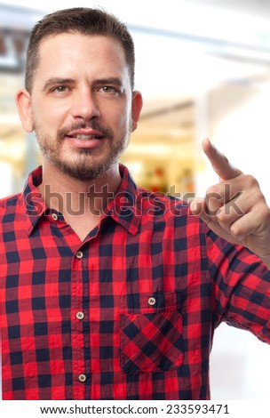 Man with red shirt over shopping center background. Pointing with his finger