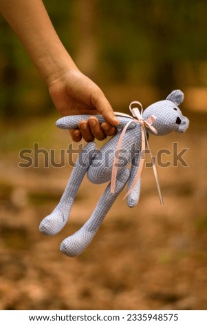 child's hand holds a soft toy bear. Photo on the street. children's problems