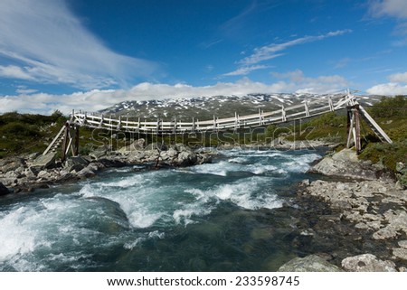 Wooden suspension footbridge over the mountain river, Norway