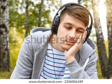Young Man in Headphones listen to the Music in the Forest Royalty-Free Stock Photo #2336006189