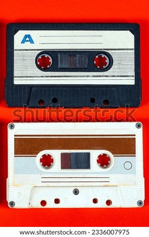 Pair of Old Audio Cassettes on Red Paper Background closeup