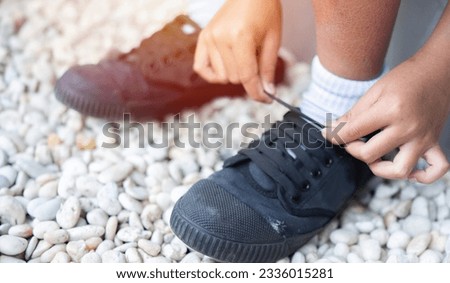 Cropped image of student boy shoes in uniform getting ready for school by tying his shoelaces. Early Education concept. Selective focus. Royalty-Free Stock Photo #2336015281