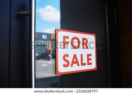 Close-up of placard For Sale hanging on the door of modern office building