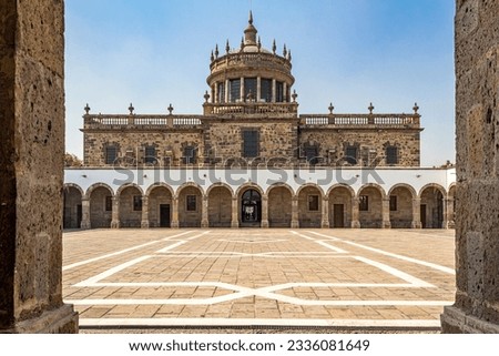 Building facade in central patio in Hospicio Cabañas against blue sky, neoclassical architecture, quarry walls, pillars, arches, corridors and wide esplanade, sunny day in Guadalajara, Jalisco Mexico Royalty-Free Stock Photo #2336081649